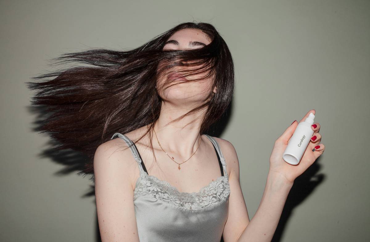 Woman misting daily mist aura eau de toilette on wrist
